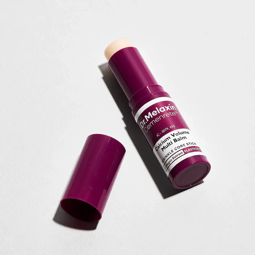 Open Multi-Balm stick with its cap beside it, on a grey background